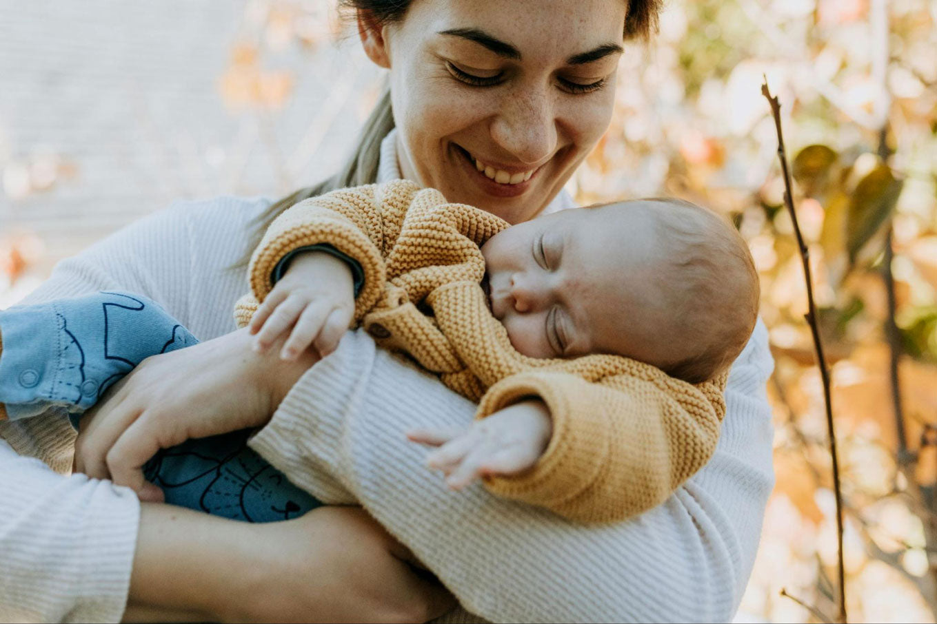 maman qui porte, son bébé qui dors, en souriant