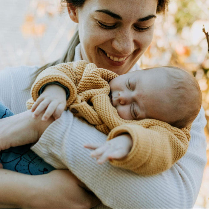 maman qui porte, son bébé qui dors, en souriant