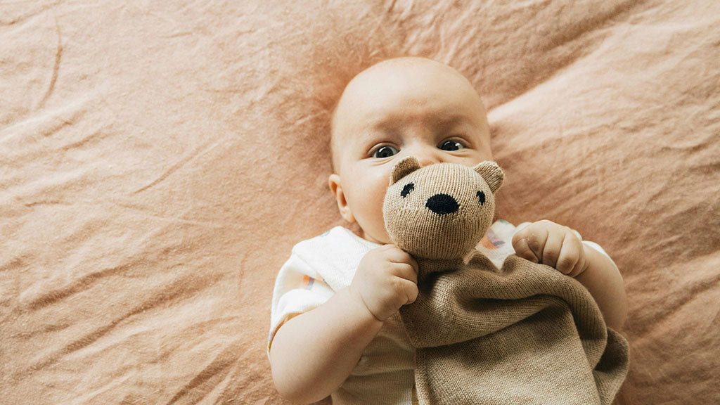 Bébé avec doudou nounours dans les bras