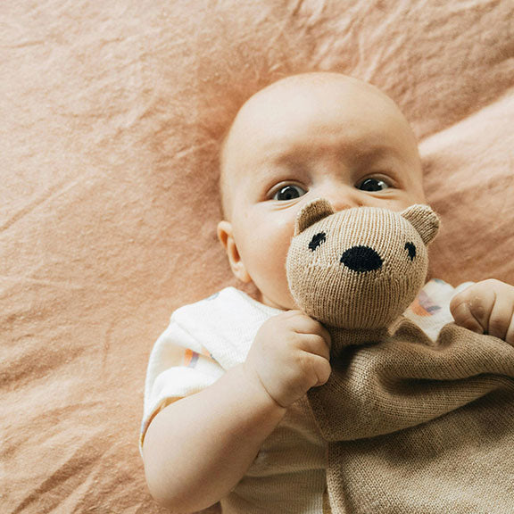 Bébé avec doudou nounours dans les bras