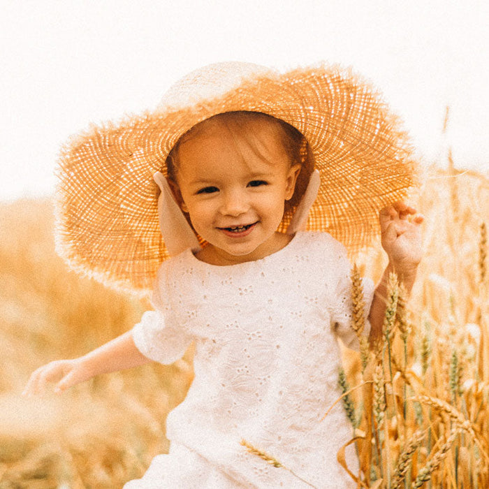 Petite fille avec chapeau de paille dans un champs de blé