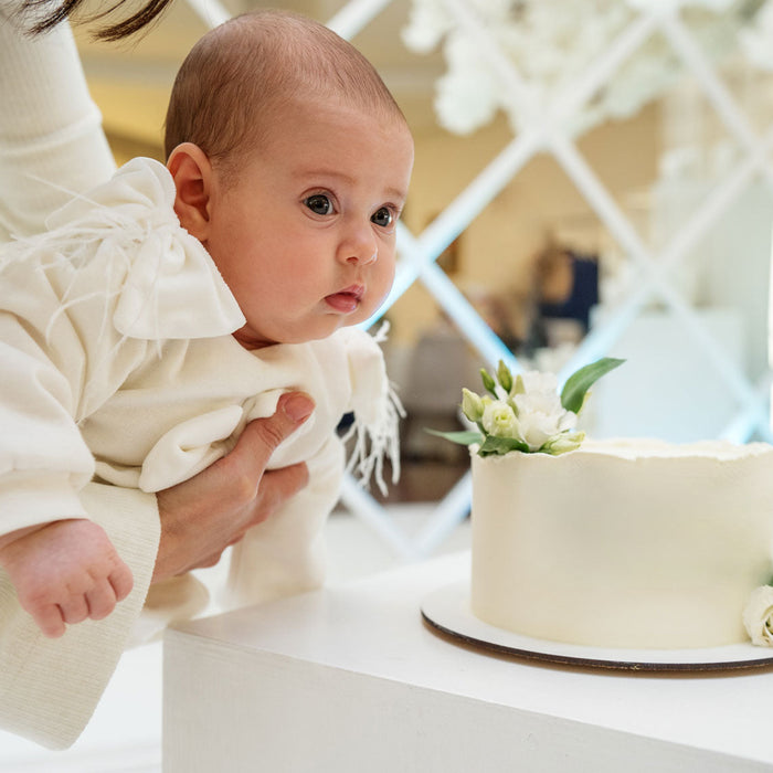 Bébé porté a côté de son gâteau de baptême