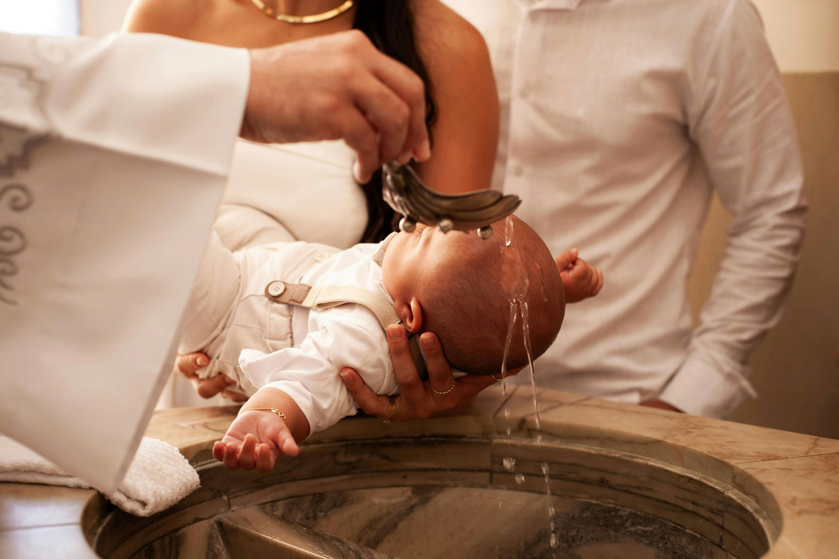 Bébé recevant l'eau bénite au dessus du bénitier