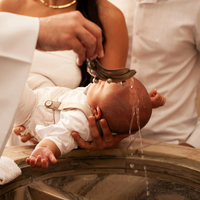 Bébé recevant l'eau bénite au dessus du bénitier