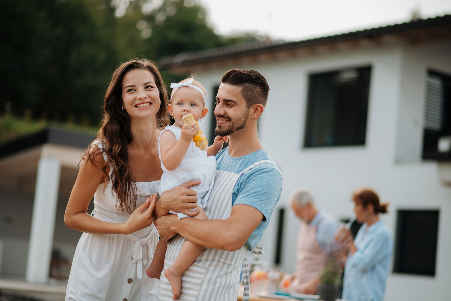 Photo article budget baptême, famille avec enfant en robe blanche. Repas de famille.