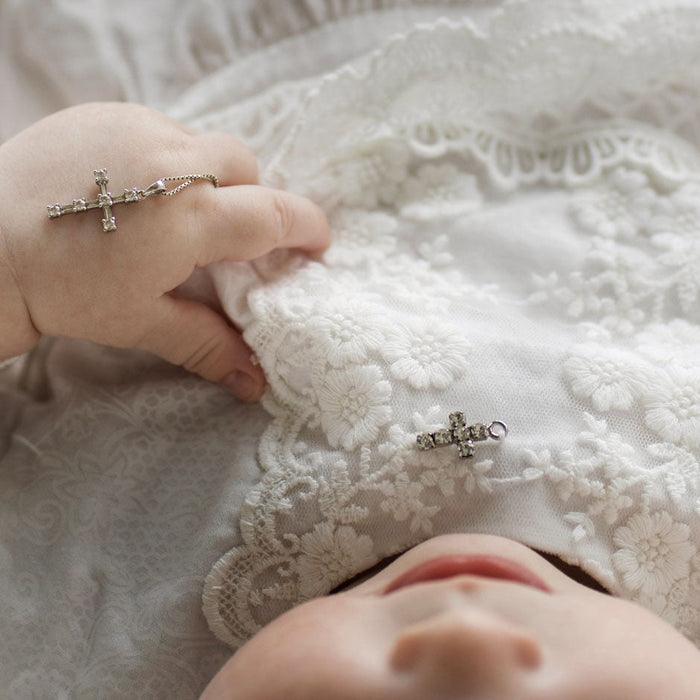 Enfant dans rode de baptême avec chapelet dans la main