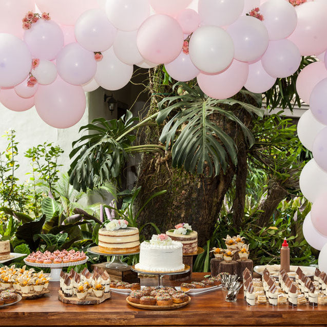 Table pour buffet sucré, avec arche de ballons pour un baptême