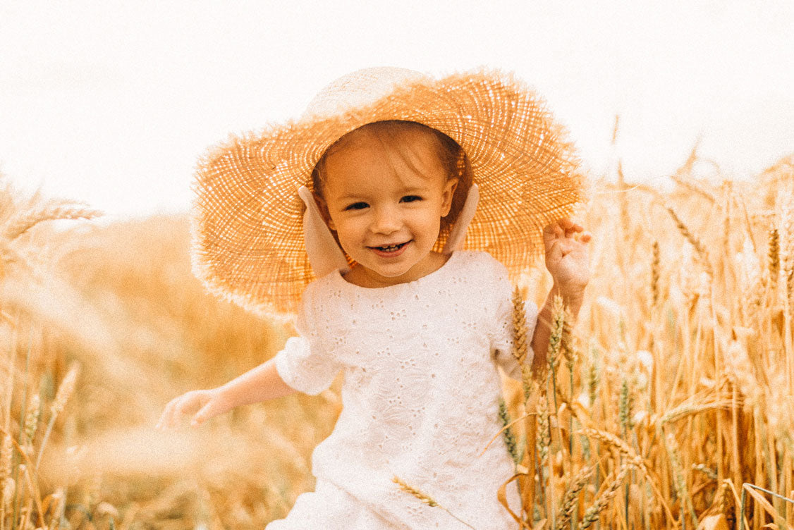 Petite fille avec chapeau de paille dans un champs de blé