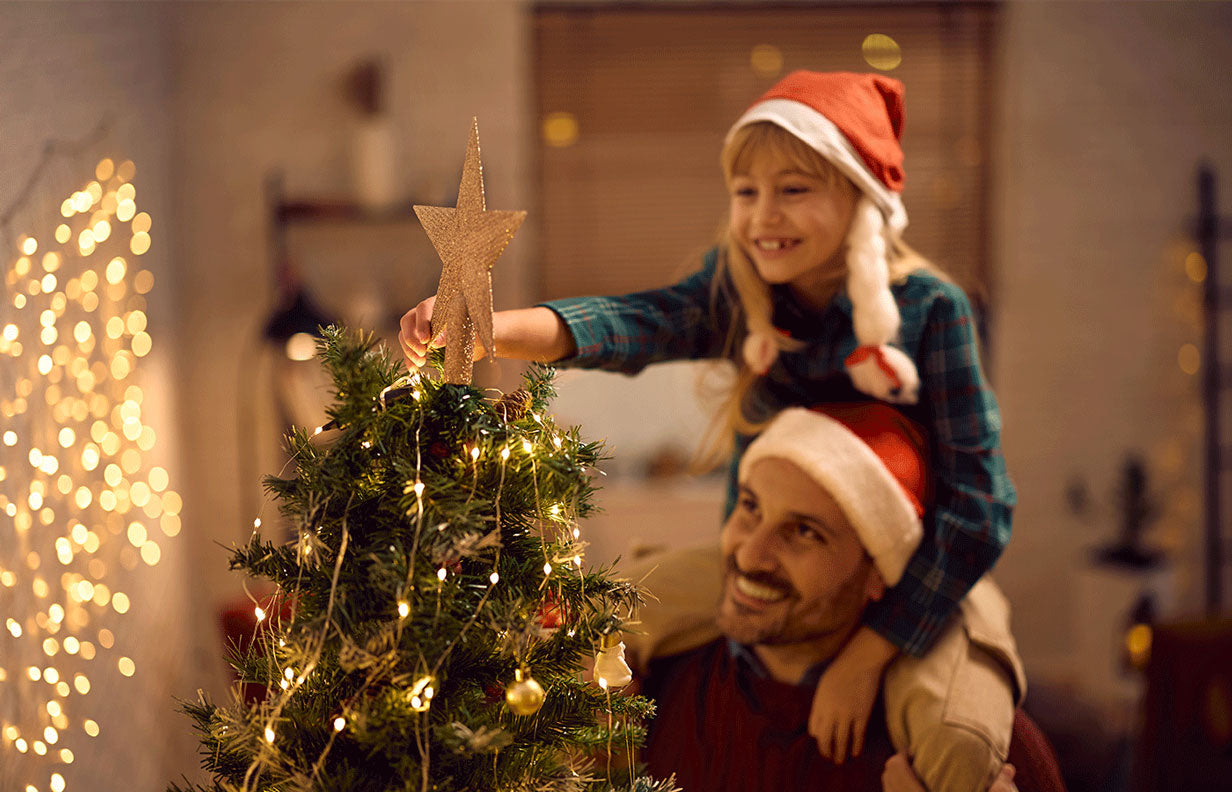 Fille et son papa entrain de décorer le sapin de Noël
