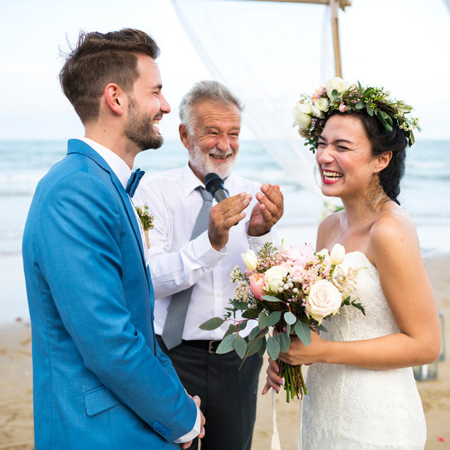 Mariés souriants sur la plage, félicités par le maitre de cérémonie