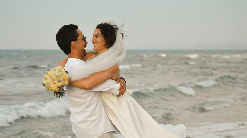 Couple d'amoureux, juste mariés, à la plage. Habillés de blanc.