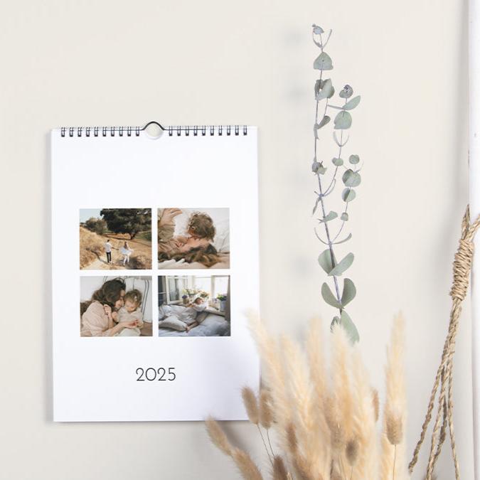 A5-Wandkalender im Hochformat, der an einer Wand hängt und auf der Titelseite geöffnet ist, die ein Raster aus vier Fotos und den Text „2025“ darunter zeigt.